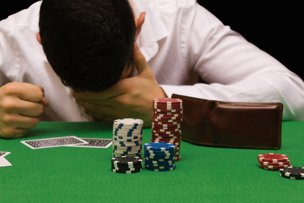 Devastated gambler man losing a lot of money playing poker in casino,