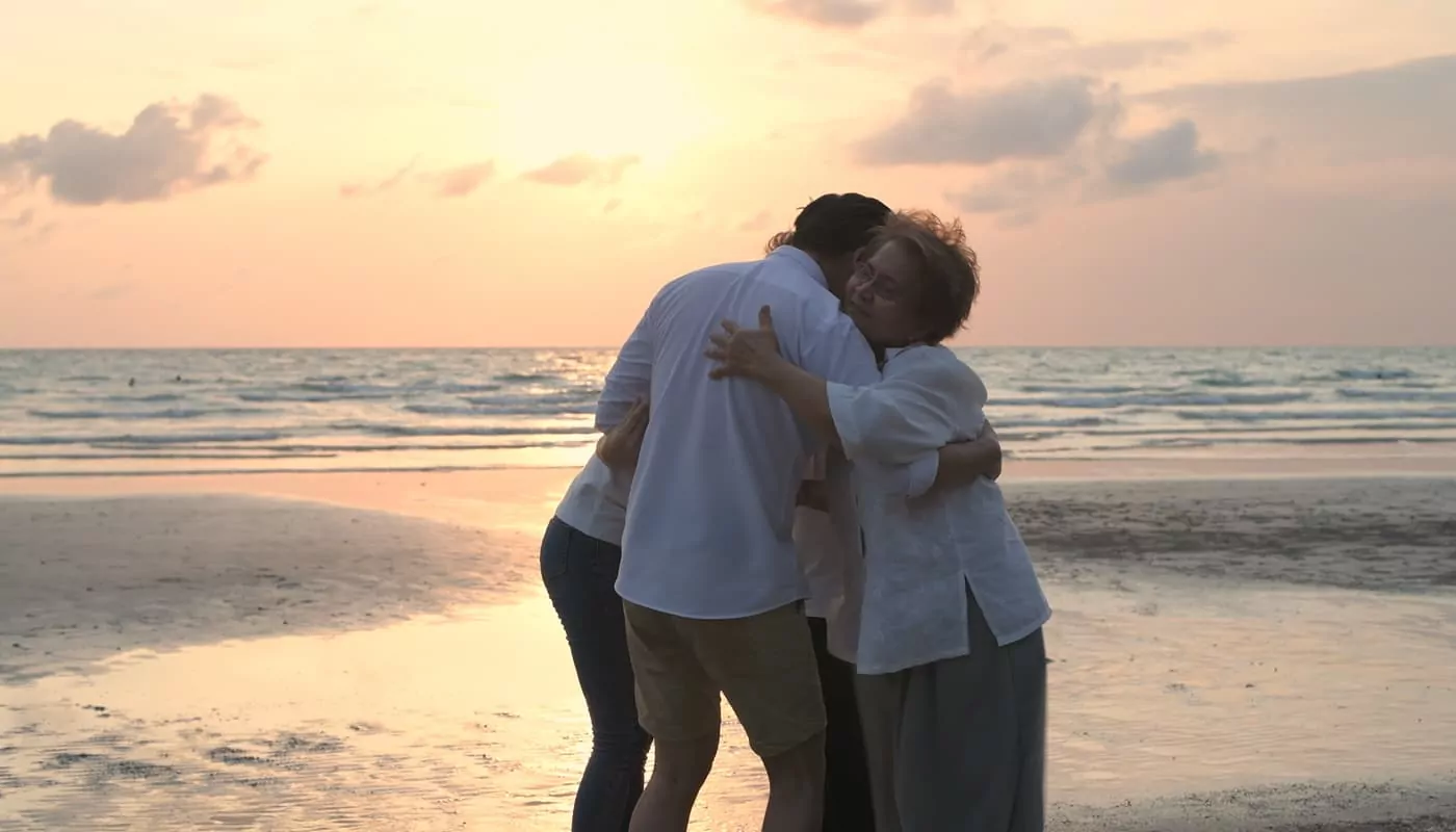 family hugging on beach